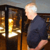 a man in a blue shirt looks at a trophy in a case