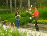 a man in a red shirt is playing a drum while a girl looks on