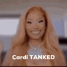 a woman with long blonde hair is sitting in a car with the words `` cardi tanked '' written on the screen .