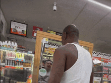 a man in a white tank top is standing in front of a sign that says buy 2 get 1 free