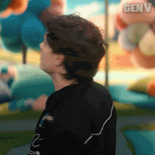a man in a black shirt is standing in front of a painting with the word genv on it