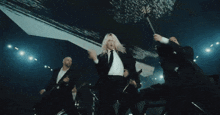 a man in a suit is holding a gun while a woman in a white shirt is playing a guitar