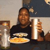 a woman wearing a shirt that says big getter is holding a cup and a plate of food