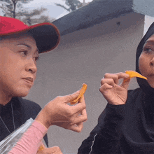 a woman in a red hat is eating a piece of food