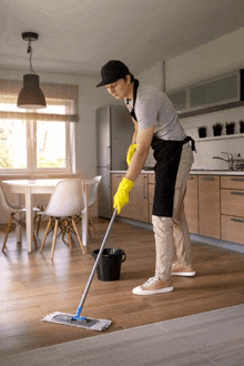 a man wearing yellow gloves is cleaning the floor with a mop .