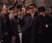 a group of men in suits and hats are standing in a line .