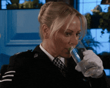 a woman in a police uniform drinks from a glass