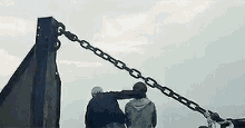a couple of people standing next to each other on top of a metal pole .