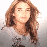 a young woman wearing a necklace and a white shirt is smiling .
