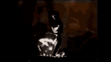 a man is dancing on a stage in a dark room in a video clip .