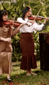 two women are playing violins in a garden with the number 070 on the bottom