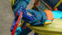 a person is holding a blue and red toy gun with a sticker that says ' a ' on it