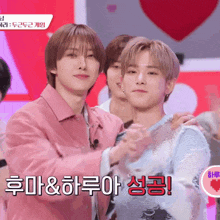 a man in a pink jacket is hugging another man in a blue sweater