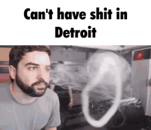 a man with a beard is looking at a smoke ring with the words " can 't have shit in detroit "