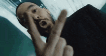 a man with a beard is making a peace sign with his fingers .