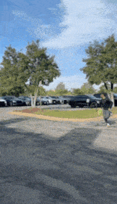 a person is walking in a parking lot with cars parked behind them