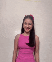 a woman in a pink dress is smiling and looking at the camera .