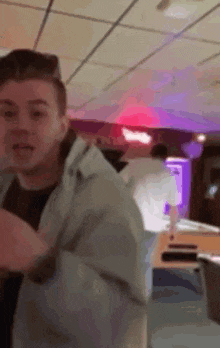 a man in a white jacket is standing in a room with a red light on the ceiling .