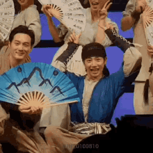 a group of people are posing for a picture while holding fans and signs .