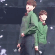 two young men in green shirts are standing next to each other on stage .