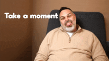 a man sitting in a chair with the words " take a moment " behind him