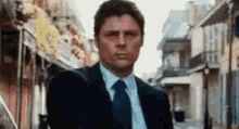 a man in a suit and tie is standing in a narrow alleyway .