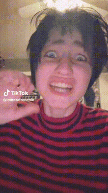 a woman wearing a red and black striped shirt has a tiktok sticker on her face