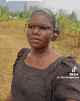 a woman wearing glasses and a headband is standing in a field with a tiktok watermark