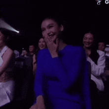 a woman in a blue dress is sitting in a dark room .
