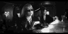 a black and white photo of a woman sitting at a bar