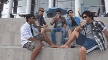 a group of young men sit on concrete steps drinking water