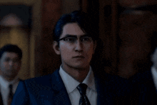 a man in a suit and tie with glasses is looking at the camera with a surprised look on his face