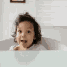 a little girl is sitting at a table giving a thumbs up .