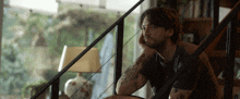 a man with a tattoo on his arm sits on a staircase