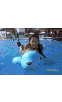 a girl in a pool with a blue whale float