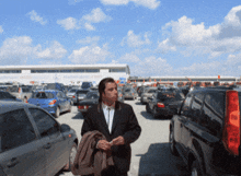 a man in a suit stands in a parking lot with a building in the background that says express auto