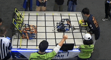 a group of people are playing a game with a robot on a table with a sign that says pman ation