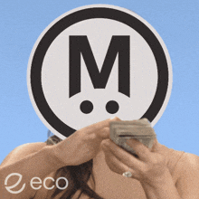 a woman holding a bunch of money in front of a sign that says m