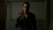 a man in a leather jacket is holding a bat .