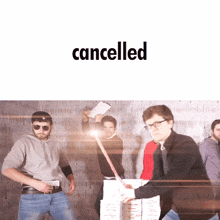 a group of men are standing in front of a wall with the word cancelled on it