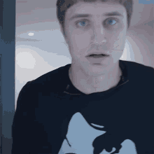 a man wearing a black sweater with a white cat on it
