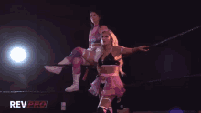 two women in a wrestling ring with revpro written on the bottom right