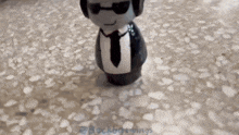 a figurine of a man in a suit and tie is standing on a tile floor
