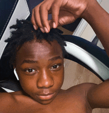 a young boy without a shirt is holding his hair