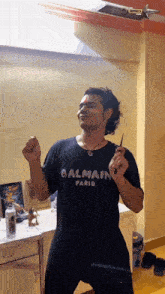 a man in a black balmain paris shirt is dancing