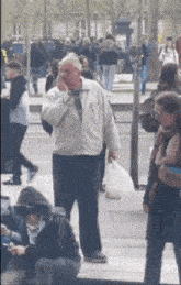 a man in a white jacket is talking on a cell phone in a crowded street