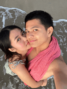 a man with a pink towel around his neck kisses a woman