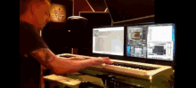 a man with a tattoo on his arm is playing a keyboard in front of two monitors