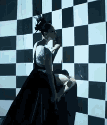 a woman in a black and white checkered dress is standing in front of a checkered wall