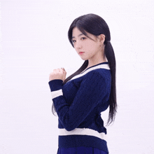 a woman in a blue and white sweater is standing with her hands folded
